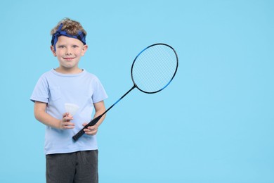 Photo of Little boy with badminton racket and shuttlecock on light blue background