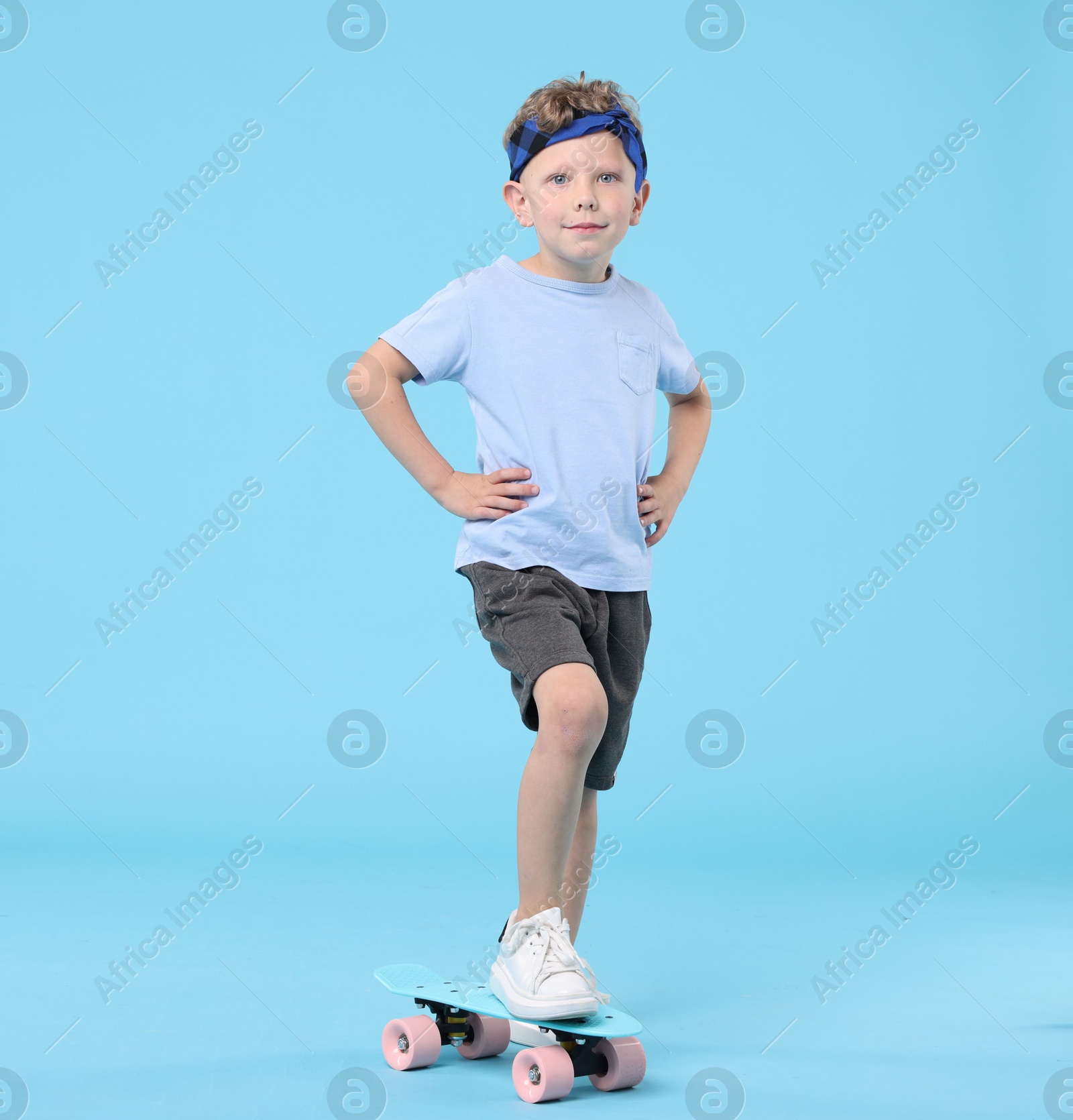 Little boy with penny board on light blue background Photo of Little boy with penny board on light blue background
