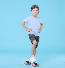 Photo of Little boy with penny board on light blue background