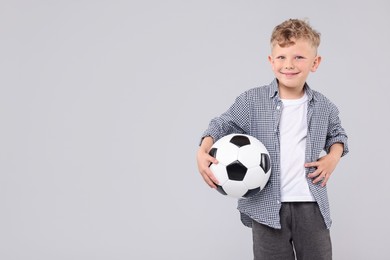Photo of Little boy with soccer ball on gray background, space for text