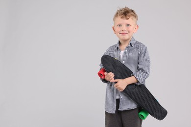 Photo of Little boy with penny board up on gray background, space for text