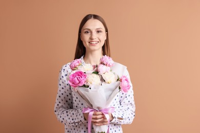 Photo of Woman with beautiful bouquet of peonies on dark beige background
