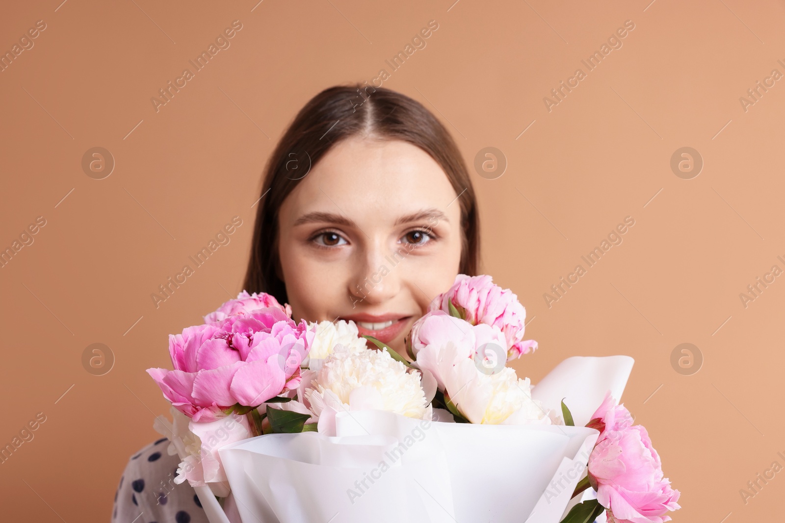 Woman with beautiful bouquet of peonies on dark beige background Photo of Woman with beautiful bouquet of peonies on dark beige background