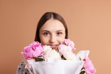 Photo of Woman with beautiful bouquet of peonies on dark beige background