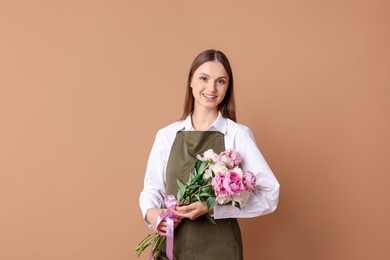 Photo of Florist with beautiful bouquet of peonies on dark beige background