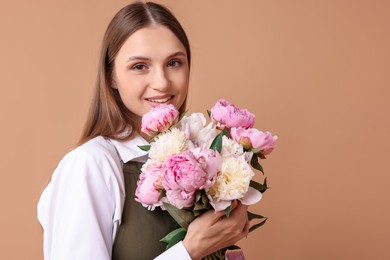 Photo of Florist with beautiful bouquet of peonies on dark beige background, space for text