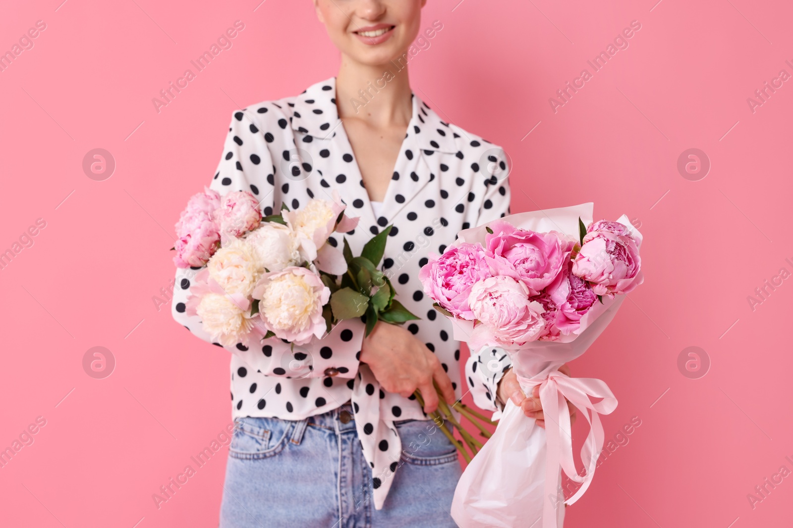 Photo of Woman with beautiful bouquets of peonies on pink background, closeup