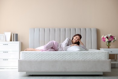Photo of Woman lying on bed with orthopedic mattress at home