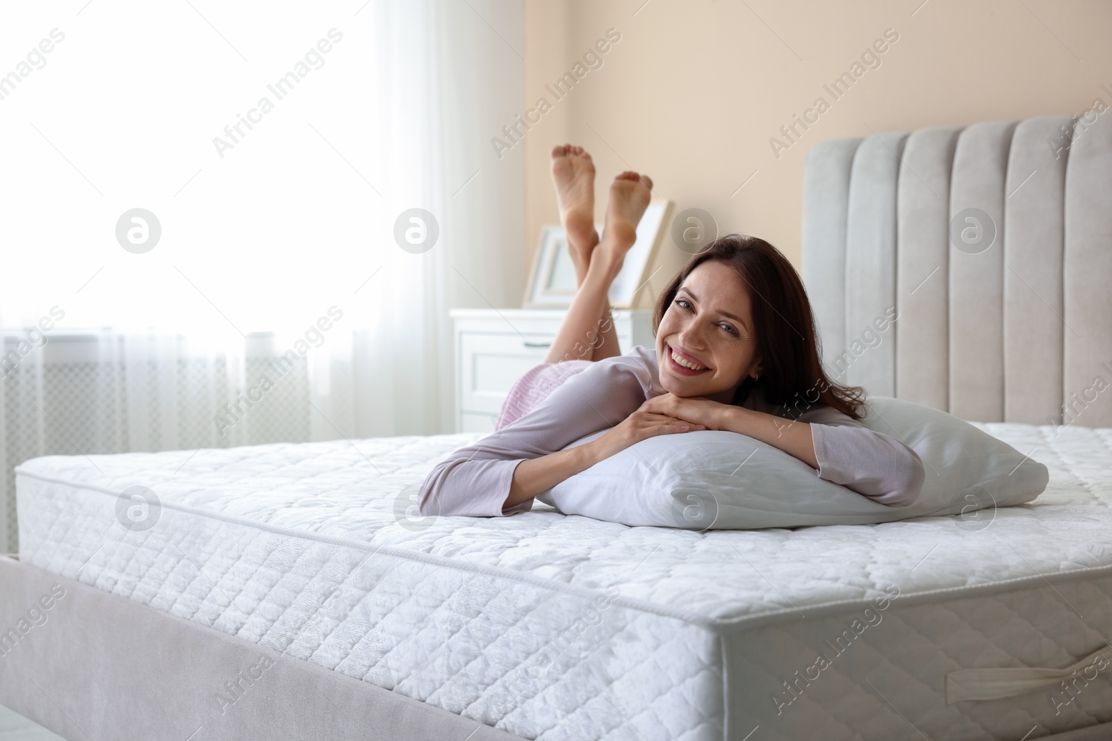 Woman lying on bed with orthopedic mattress at home. Space for text Photo of Woman lying on bed with orthopedic mattress at home. Space for text