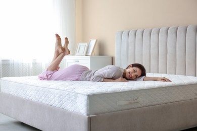 Photo of Woman lying on bed with orthopedic mattress at home