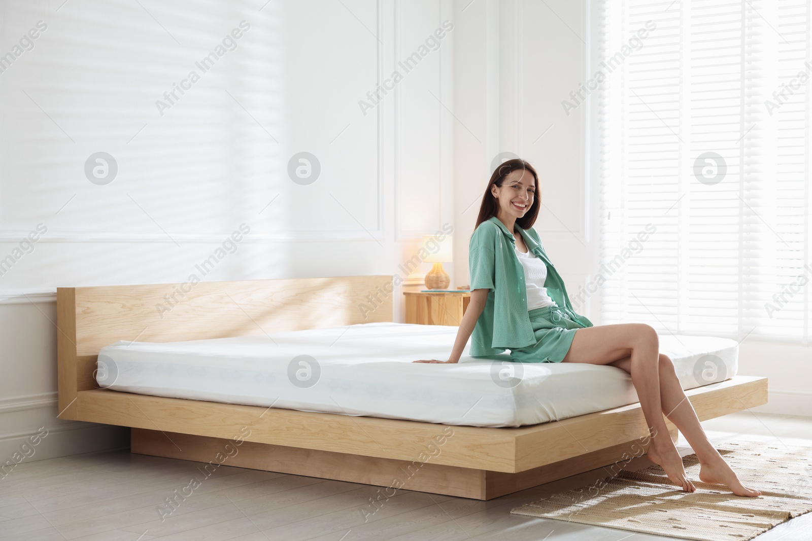 Woman on bed with soft mattress at home. Space for text Photo of Woman on bed with soft mattress at home. Space for text