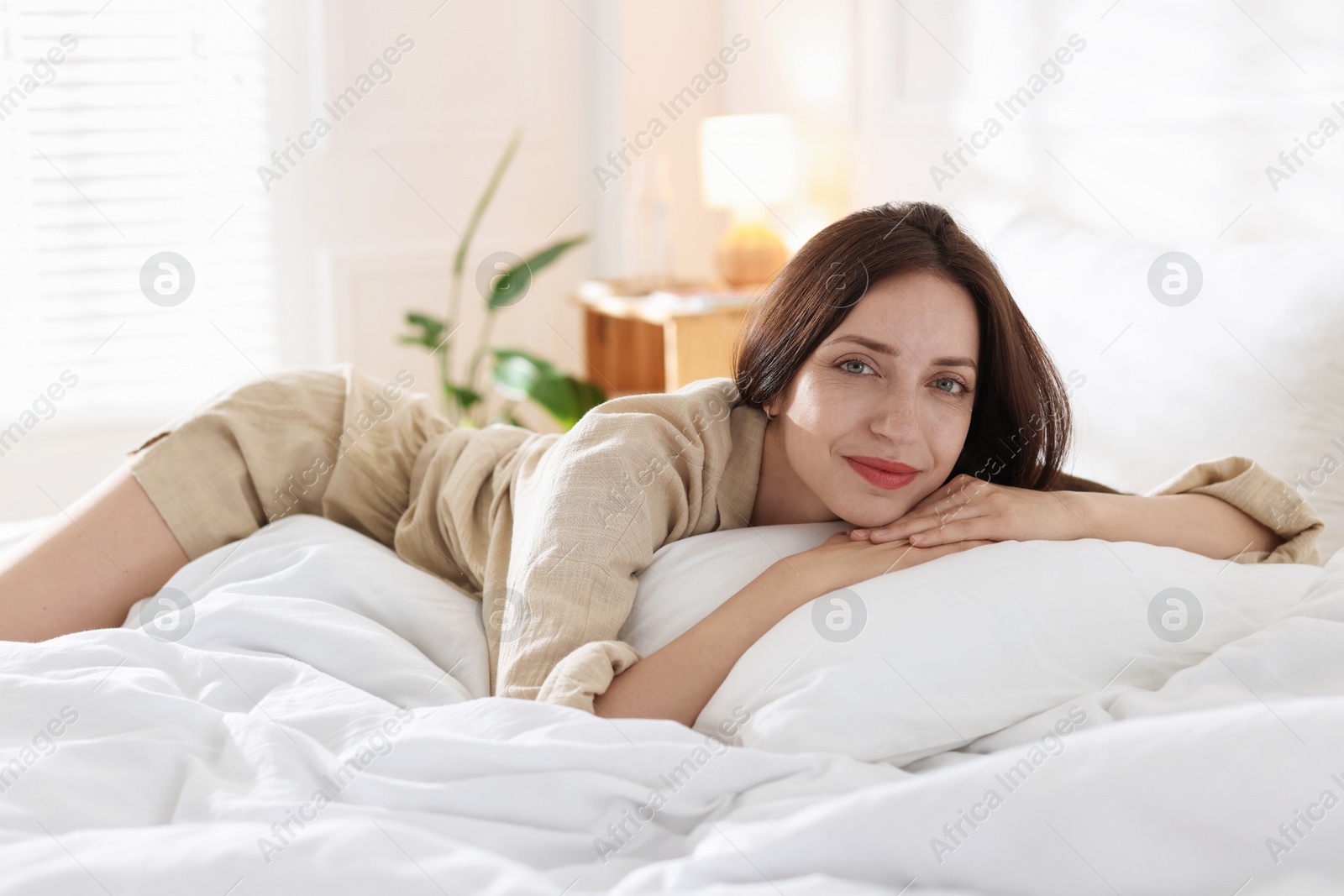 Woman lying on bed with soft mattress at home Photo of Woman lying on bed with soft mattress at home