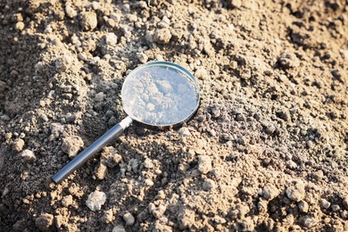 Photo of Magnifying glass on dry soil in field
