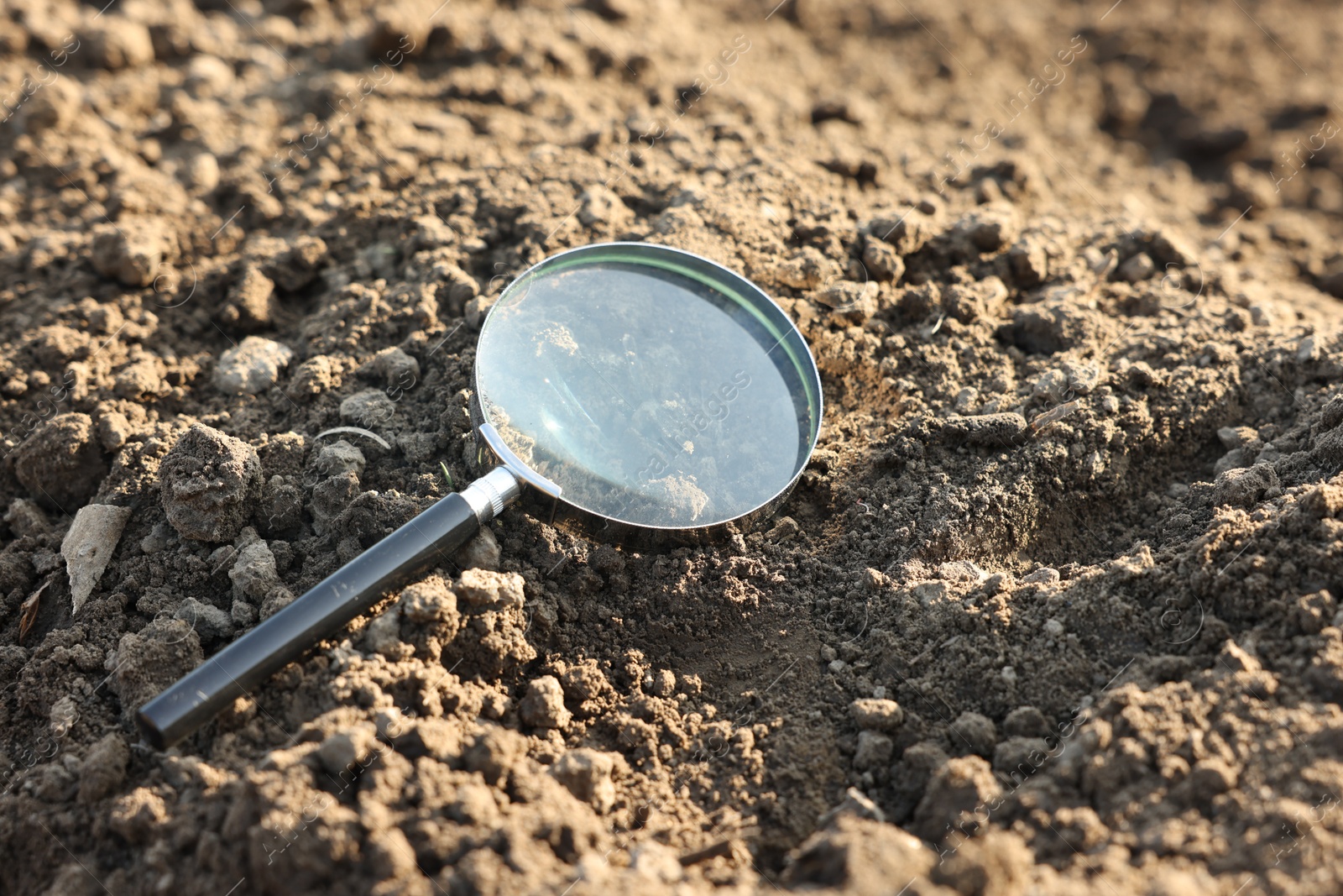Magnifying glass on dry soil in field Photo of Magnifying glass on dry soil in field