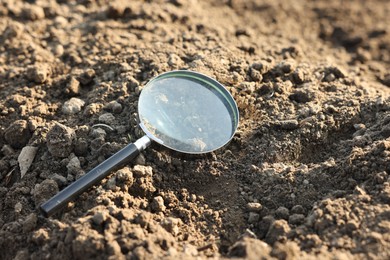 Photo of Magnifying glass on dry soil in field
