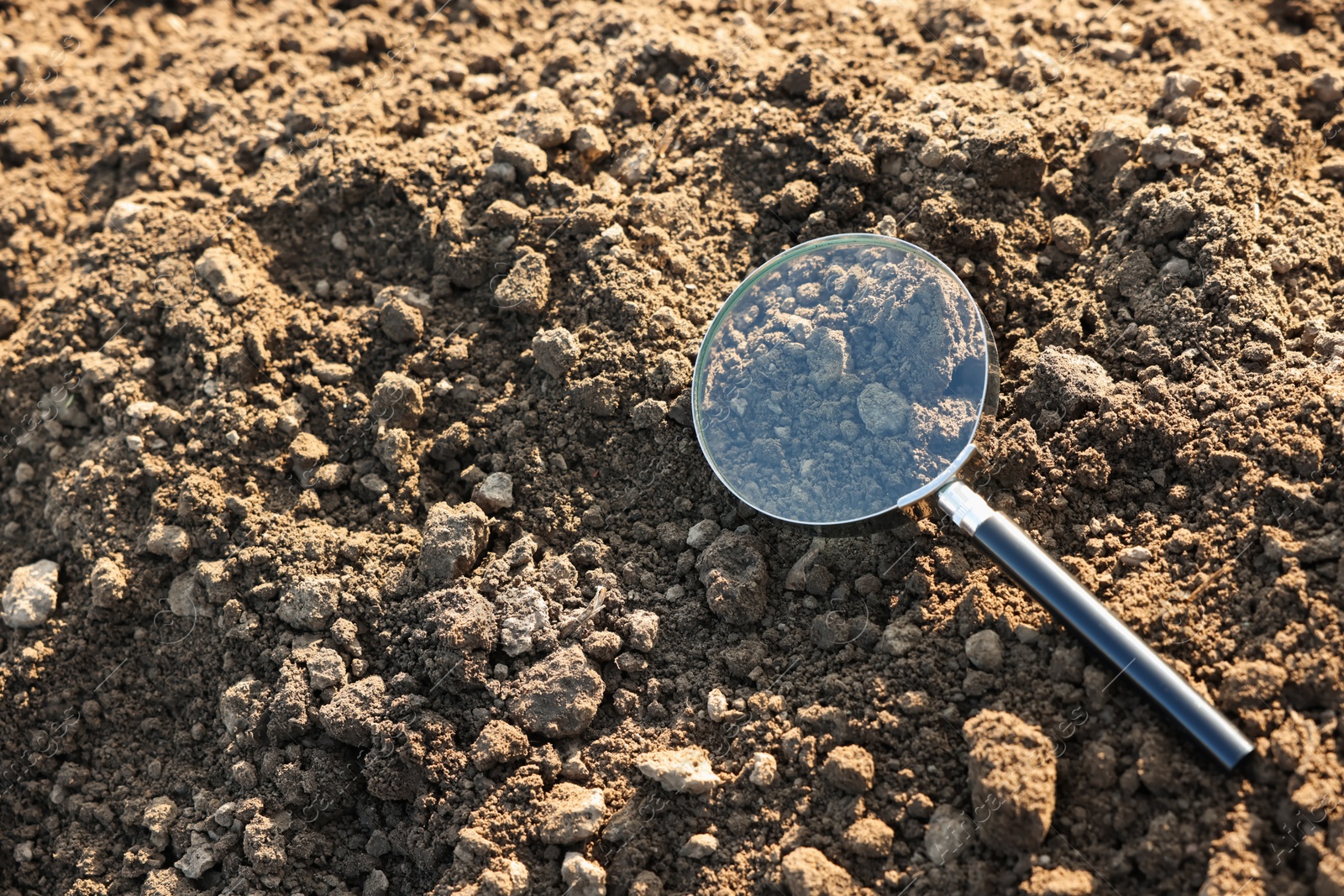 Magnifying glass on dry soil in field, above view. Space for text Photo of Magnifying glass on dry soil in field, above view. Space for text