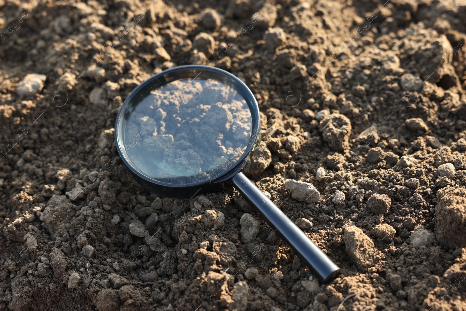 Magnifying glass on dry soil in field, closeup Photo of Magnifying glass on dry soil in field, closeup