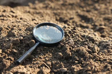 Photo of Magnifying glass on dry soil in field