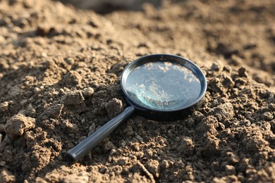 Photo of Magnifying glass on dry soil in field