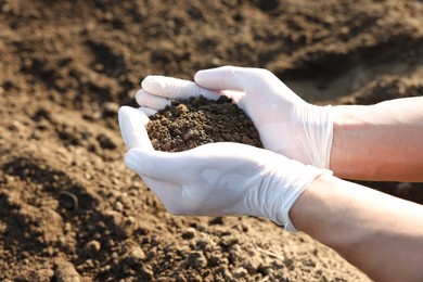 Photo of Man holding pile of soil outdoors, closeup