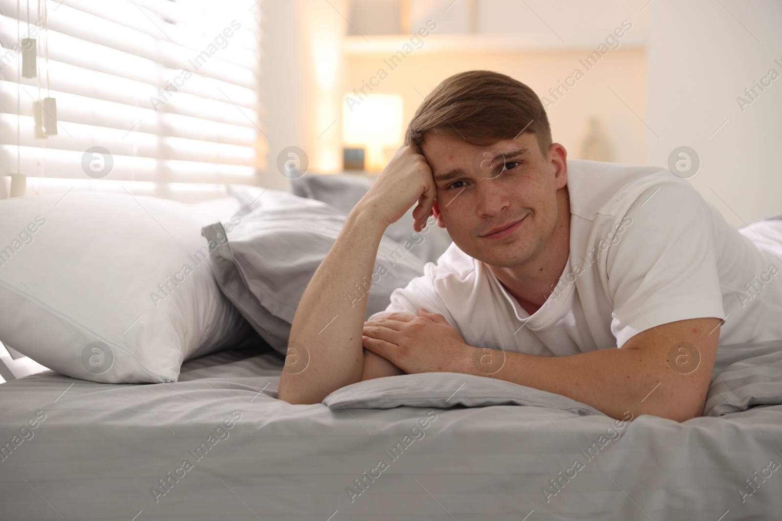 Young man lying on bed with soft mattress at home, space for text Photo of Young man lying on bed with soft mattress at home, space for text