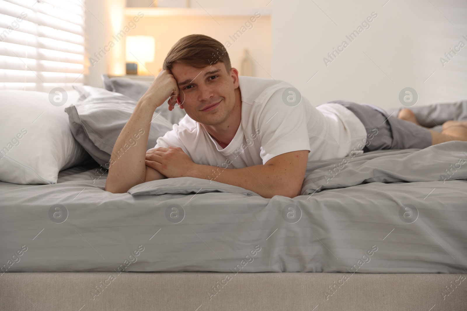 Young man lying on bed with soft mattress at home Photo of Young man lying on bed with soft mattress at home