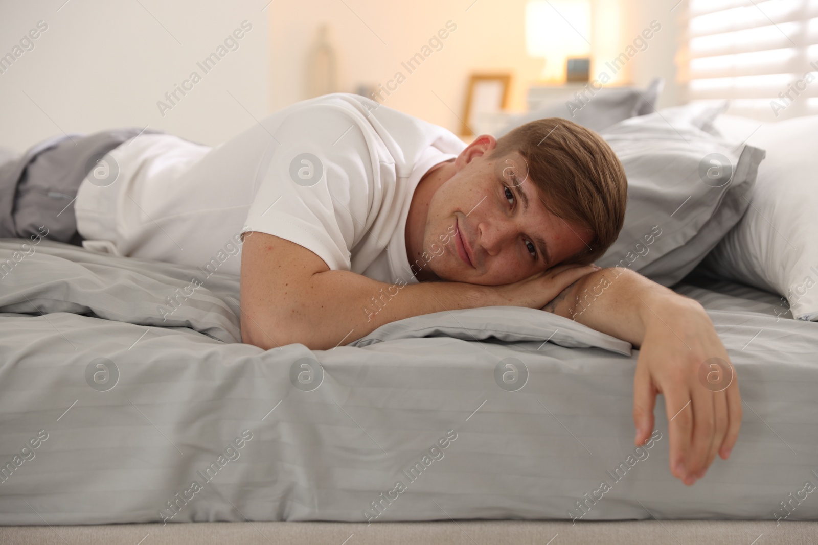 Young man lying on bed with soft mattress at home Photo of Young man lying on bed with soft mattress at home