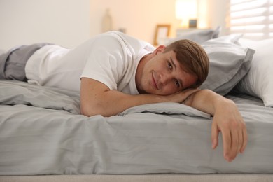 Photo of Young man lying on bed with soft mattress at home