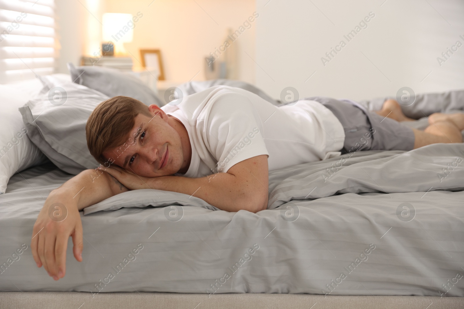 Young man lying on bed with soft mattress at home Photo of Young man lying on bed with soft mattress at home