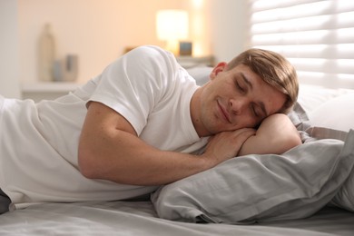 Photo of Young man sleeping on bed with soft mattress at home