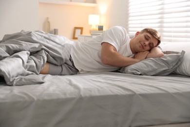 Photo of Young man sleeping on bed with soft mattress at home