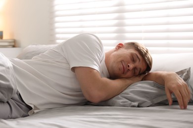 Photo of Young man sleeping on bed with soft mattress at home