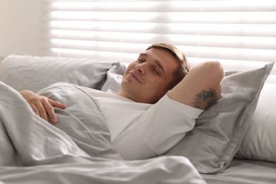 Photo of Young man sleeping on bed with soft mattress at home