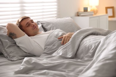 Photo of Young man sleeping on bed with soft mattress at home