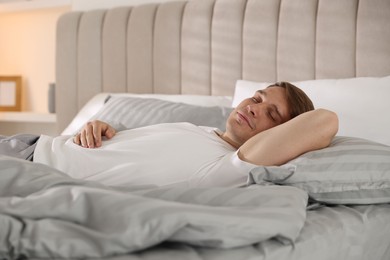 Photo of Young man sleeping on bed with soft mattress at home