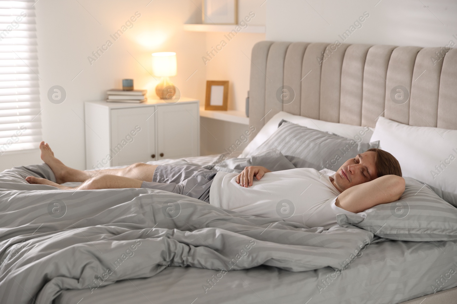 Young man sleeping on bed with soft mattress at home Photo of Young man sleeping on bed with soft mattress at home