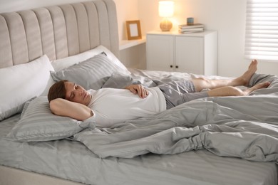 Photo of Young man sleeping on bed with soft mattress at home