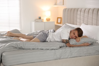 Photo of Young man sleeping on bed with soft mattress at home