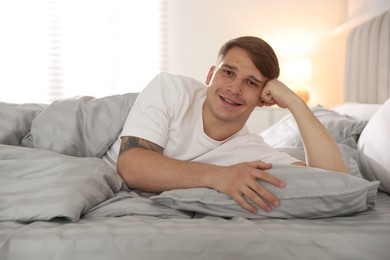 Photo of Young man lying on bed with soft mattress at home