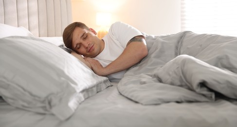 Photo of Young man sleeping on bed with soft mattress at home
