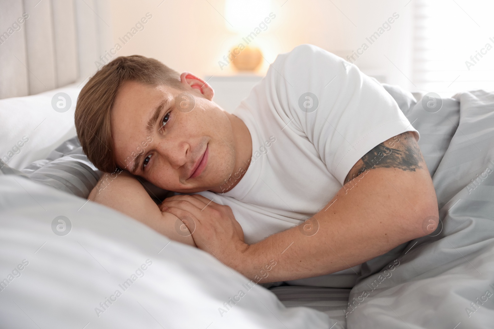 Young man lying on bed with soft mattress at home Photo of Young man lying on bed with soft mattress at home