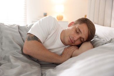 Photo of Young man lying on bed with soft mattress at home