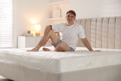 Photo of Young man sitting on bed with soft mattress at home