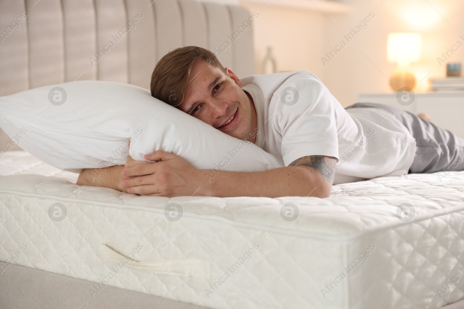 Young man lying on bed with soft mattress at home Photo of Young man lying on bed with soft mattress at home