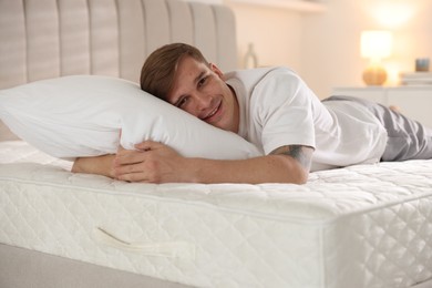 Photo of Young man lying on bed with soft mattress at home