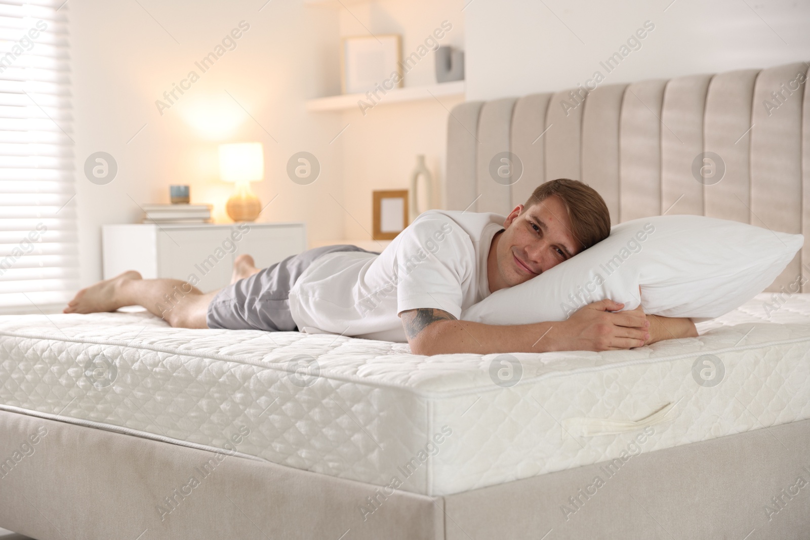 Young man lying on bed with soft mattress at home Photo of Young man lying on bed with soft mattress at home