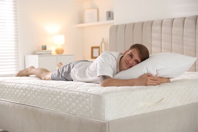 Photo of Young man lying on bed with soft mattress at home