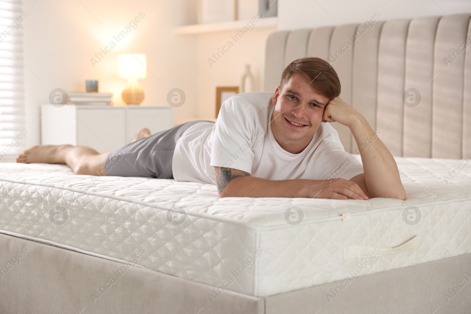 Young man lying on bed with soft mattress at home Photo of Young man lying on bed with soft mattress at home