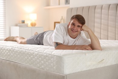 Photo of Young man lying on bed with soft mattress at home