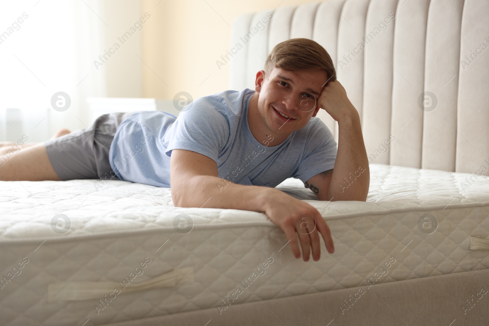Young man lying on bed with soft mattress at home Photo of Young man lying on bed with soft mattress at home